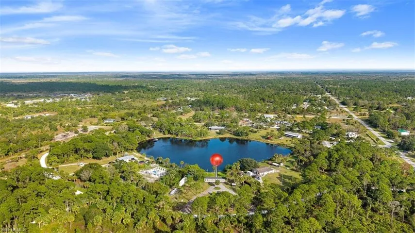 Aerial view of property and surrounding area featuring a forest and a large body of water