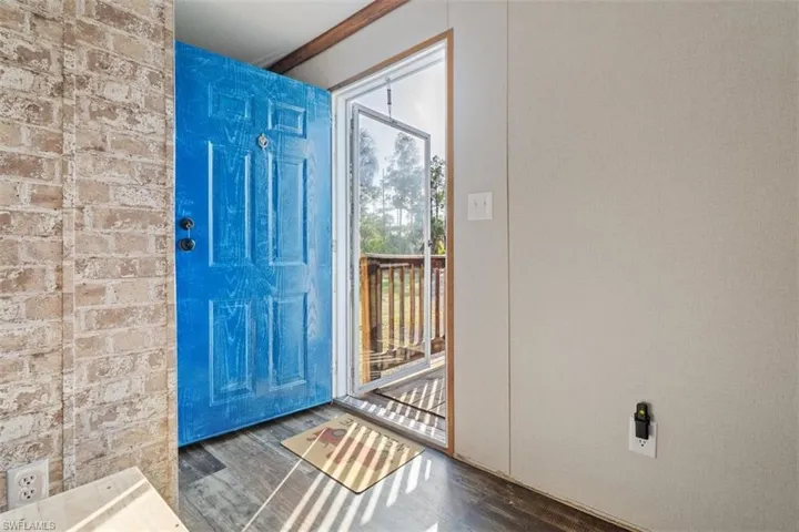Entryway with brick wall and wood finished floors