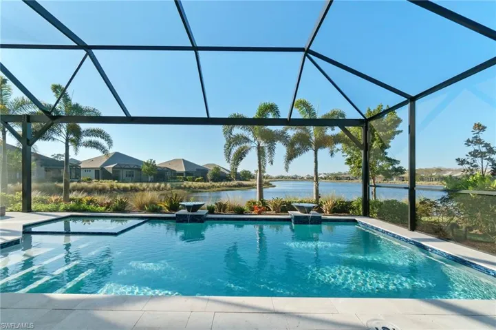 View of swimming pool with a water view, pool water feature, and glass enclosure