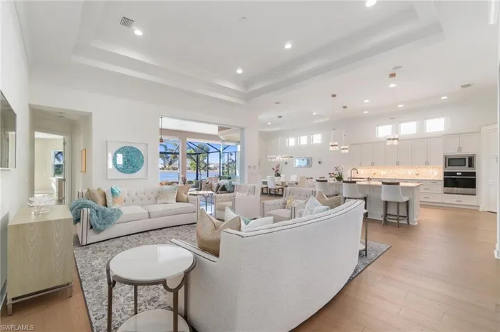 Living room with a high ceiling, light wood-type flooring, and a tray ceiling