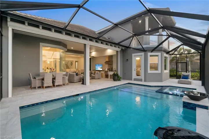 View of pool with an outdoor hangout area, glass enclosure, and a patio area