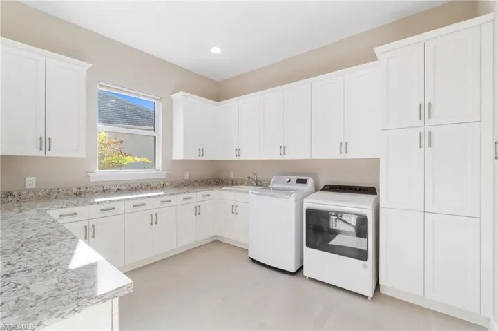 Clothes washing area with cabinets, sink, and washer and clothes dryer