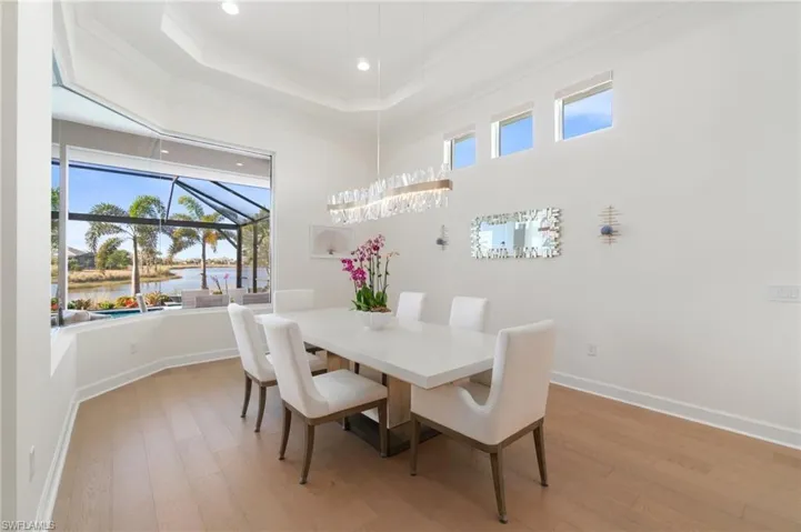 Dining space with light hardwood / wood-style flooring, ornamental molding, a raised ceiling, and a water view