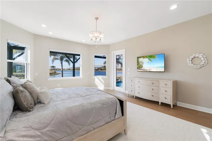 Bedroom featuring hardwood / wood-style flooring, access to exterior, and a notable chandelier