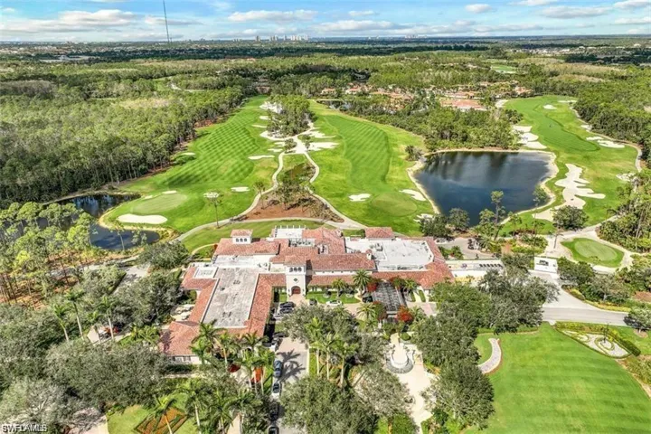 Aerial view of the club house with a tiled roof and surrounding golf course, featuring greens, bunkers, and water bodies