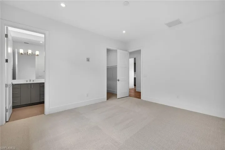 Bedroom 2 featuring a spacious closet, light carpet, recessed lighting, and en suite bathroom
