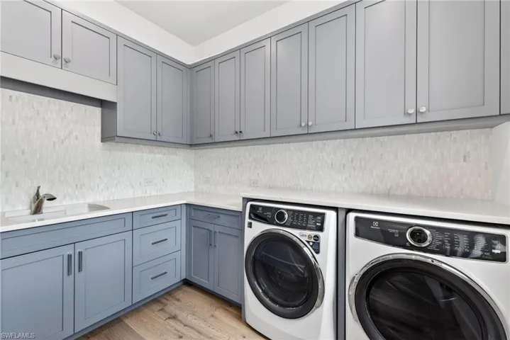 Laundry room with light  wood flooring, lots of extra cabinet space, and separate washer and dryer