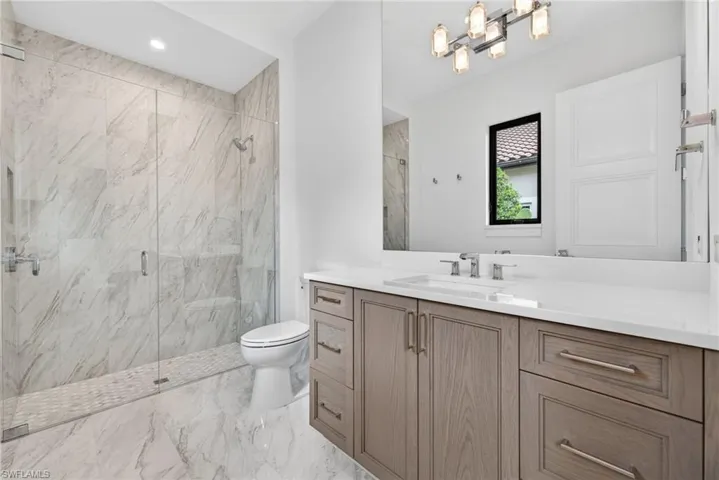 bathroom 3 with beautiful wood vanity, a marble finish shower, light marble finish floors