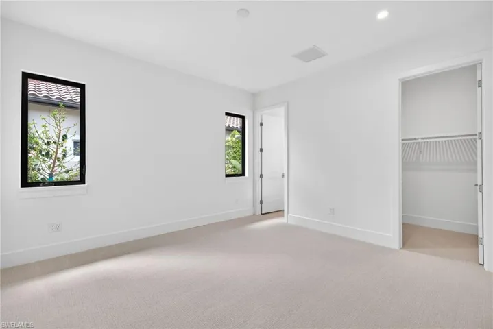 Bedroom 3 with light carpet, a walk in closet