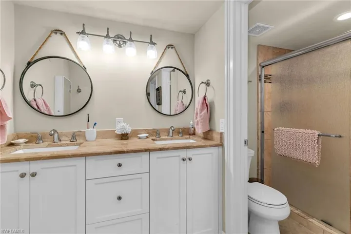 Full bath with toilet, a shower stall, and double vanity