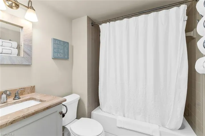Bathroom featuring shower / bath combo with shower curtain, vanity, and toilet