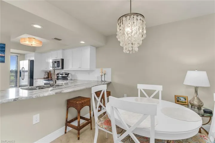 Kitchen featuring stainless steel appliances, white cabinetry, light stone counters, a peninsula, and recessed lighting
