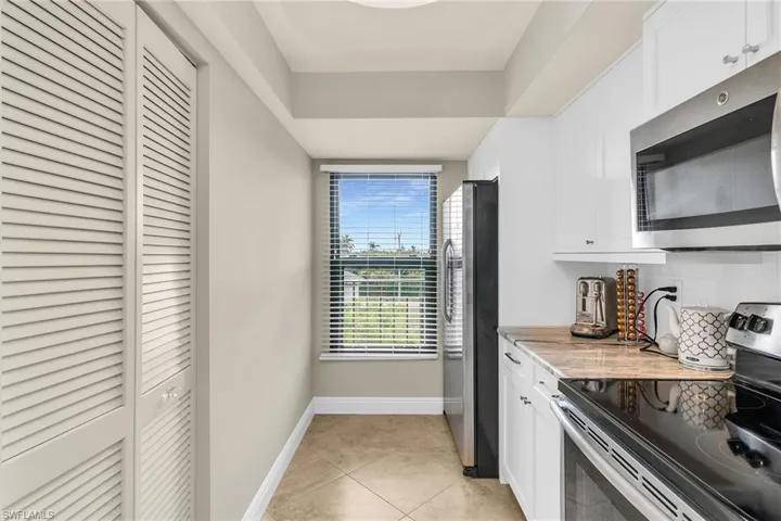 Kitchen featuring appliances with stainless steel finishes, baseboards, white cabinetry, and light tile patterned floors