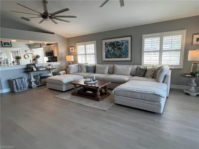Living room featuring lofted ceiling, wood-type flooring, and ceiling fan