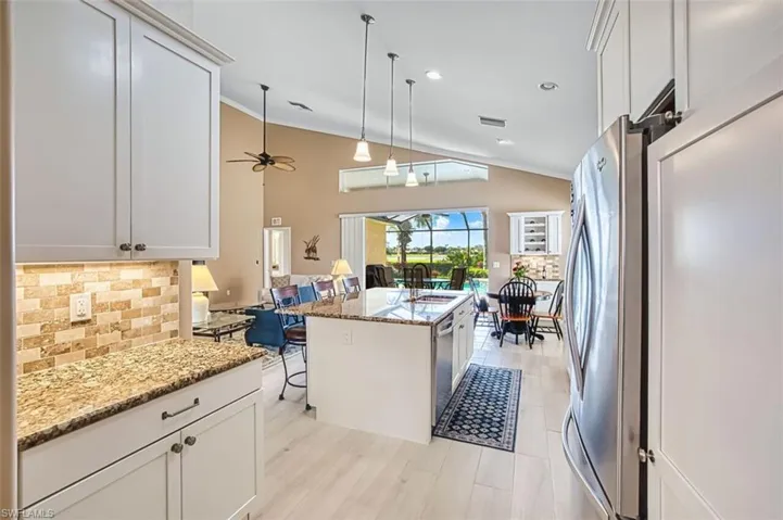 Kitchen with white cabinetry, a sunroom, light stone counters, lofted ceiling, and crown molding