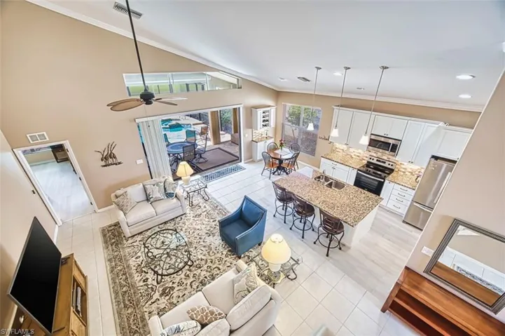 Living room with ornamental molding, light tile patterned floors, ceiling fan, and a high ceiling