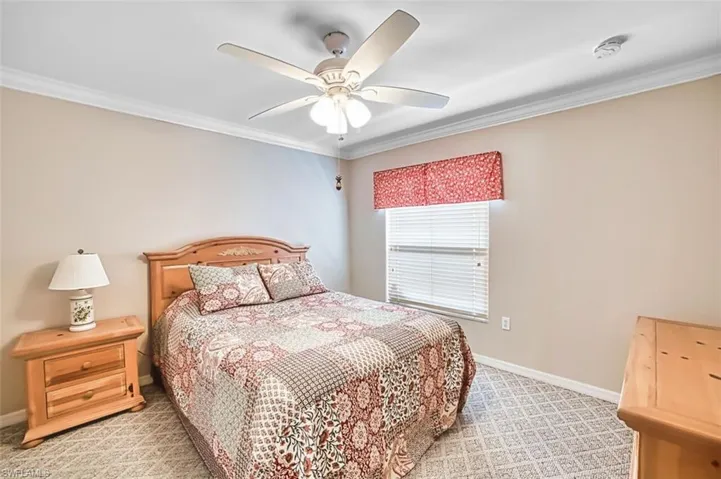Bedroom with light carpet, crown molding, and ceiling fan