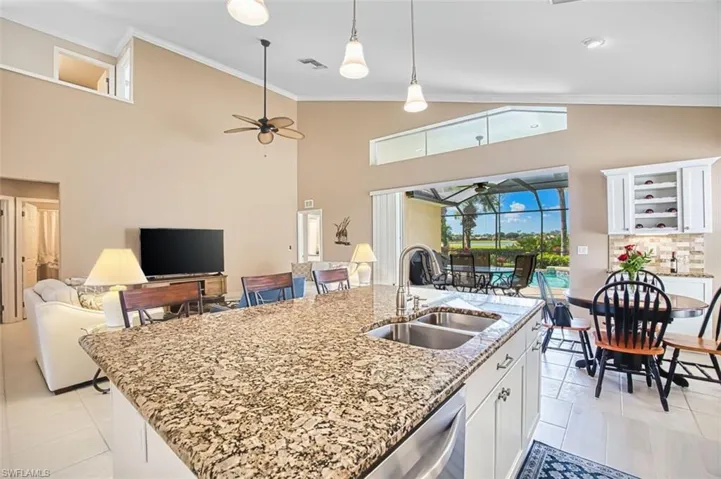 Kitchen with a sunroom, ornamental molding, white cabinetry, open floor plan, and ceiling fan
