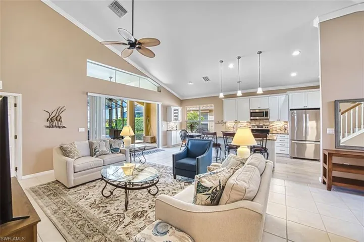 Living area with ornamental molding, vaulted ceiling, a ceiling fan, light tile patterned floors, and recessed lighting
