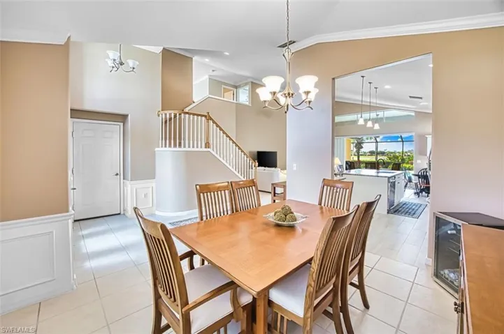Dining space featuring suspended lighting, ornamental molding, a high ceiling, light tile patterned floors, and wainscoting