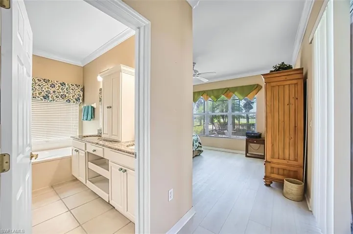 Full bath featuring ornamental molding, vanity, and a bath