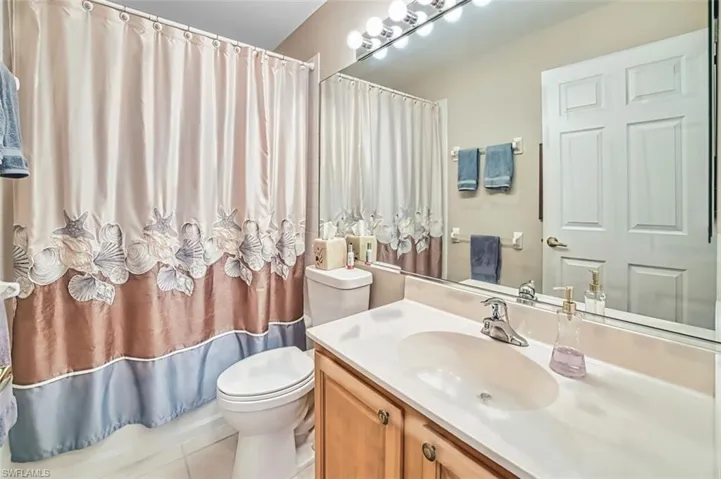 Full bathroom featuring vanity, light tile patterned floors, and curtained shower