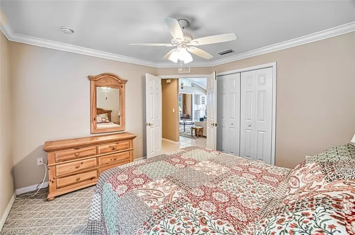 Bedroom with ornamental molding, light carpet, a closet, and ceiling fan