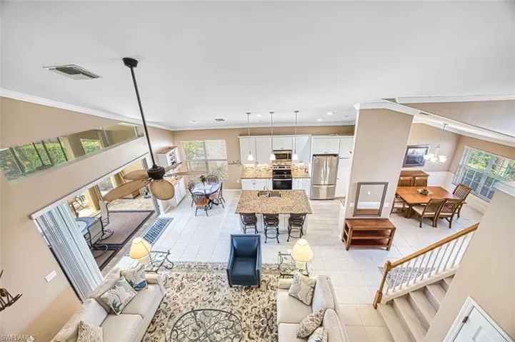 Living area featuring ornamental molding, a ceiling fan, suspended lighting, and light tile patterned floors