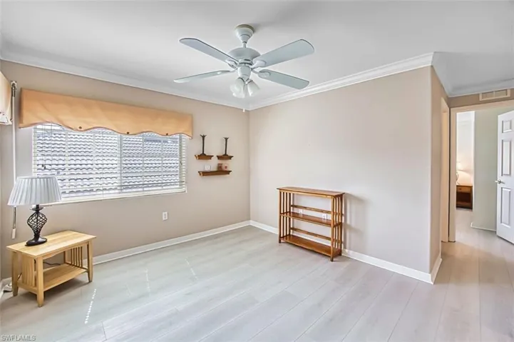 Spare room with ceiling fan, crown molding, and light wood-style flooring