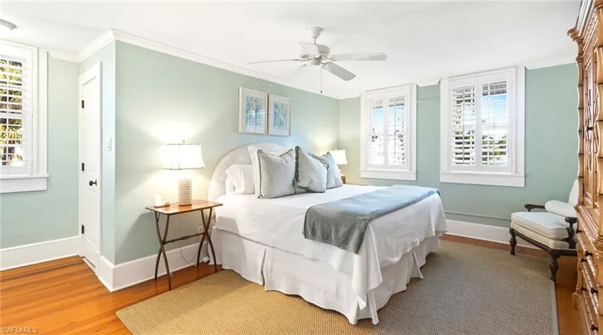 Bedroom featuring crown molding, multiple windows, light wood-style floors, and a ceiling fan
