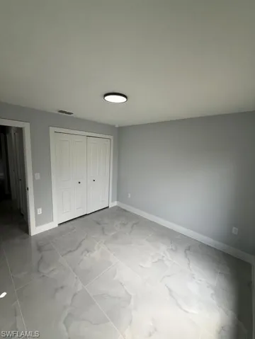 Unfurnished bedroom featuring a closet and light marble finish floors