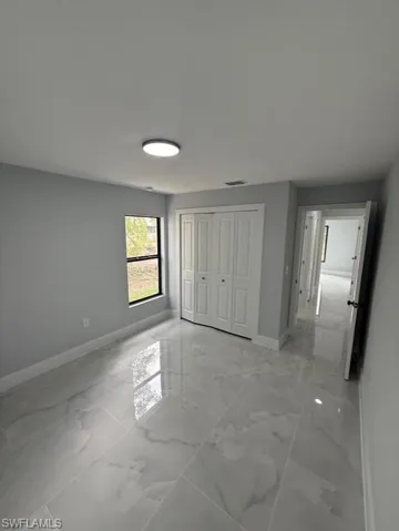 Unfurnished bedroom with a closet and light marble finish floors