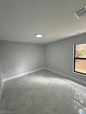 Spare room featuring baseboards and light marble finish floors