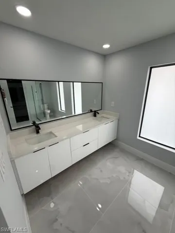 Full bath featuring double vanity, recessed lighting, and light marble finish flooring