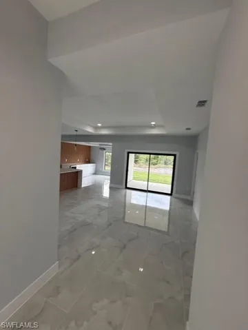 Unfurnished room featuring light marble finish floors, a tray ceiling, and recessed lighting