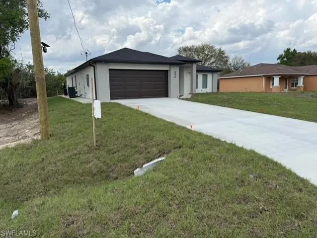 Single story home with an attached garage, driveway, a front yard, and stucco siding