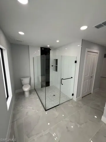 Full bath featuring a shower stall, light marble finish floors, and recessed lighting