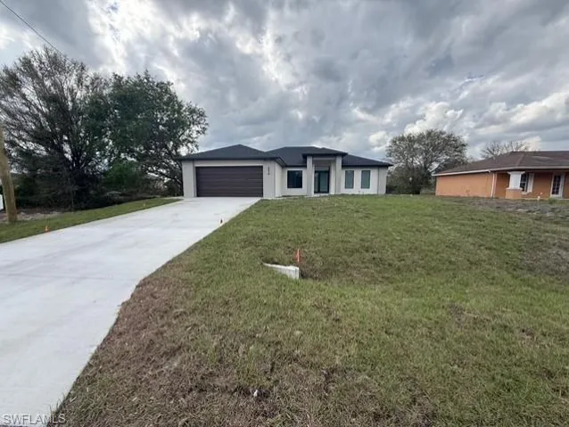 View of front of home featuring a front yard, driveway, and an attached garage