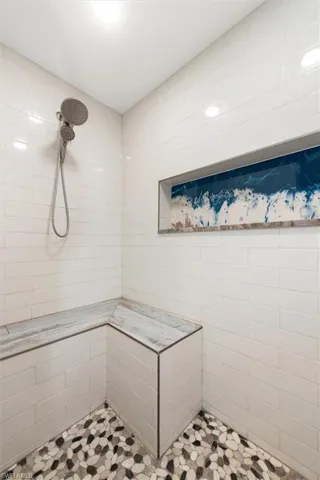 Gorgeous Master Shower with Built-in seating, stone floors, custom tile and hand crafted epoxy shower niche.