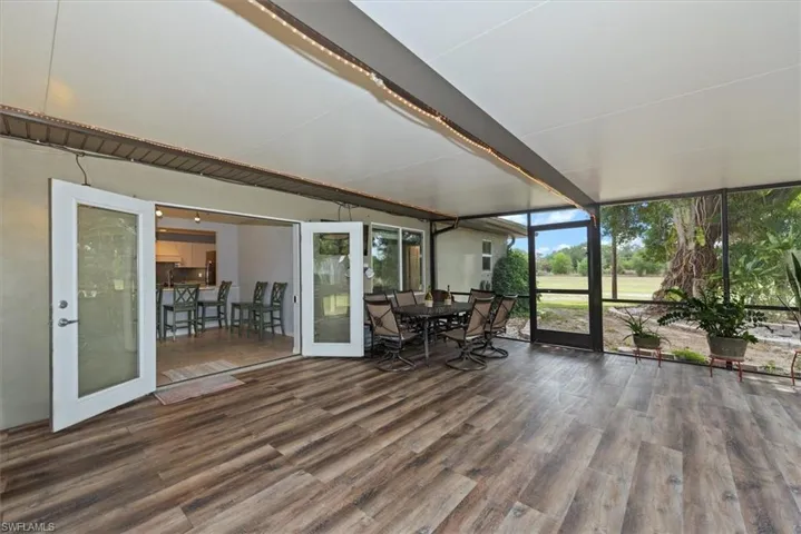 Sunroom with expansive windows, wood finished vinyl, outdoor dining space, and french doors