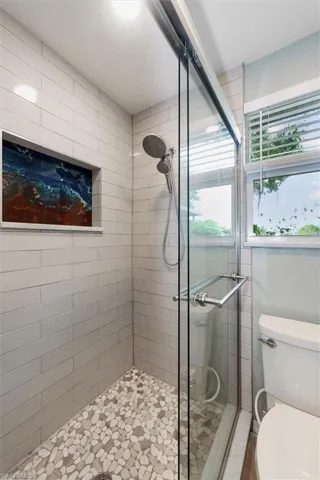 Custom Tile Shower with Sliding Glass Doors, stone floors, and hand crafted expoxy shower niche.