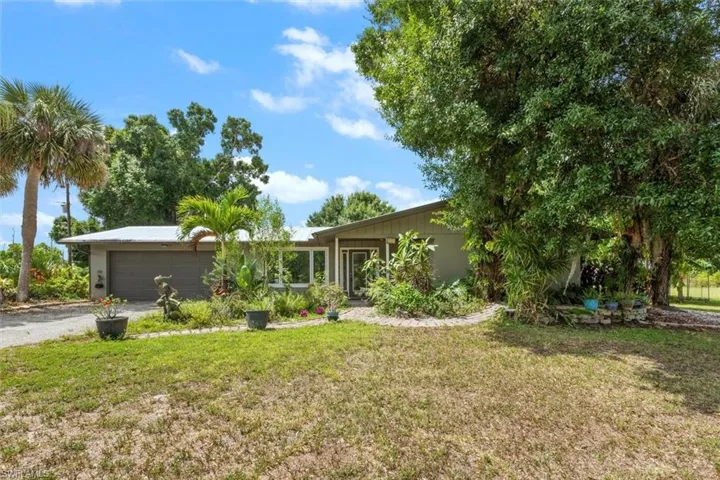 View of front of home with a garage, asphalt driveway, and a front yard