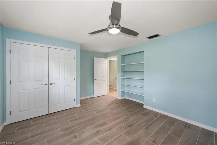 Guest Bedroom with Custom Built-in Shelving, Remote Fan and Wood Plank Tile.