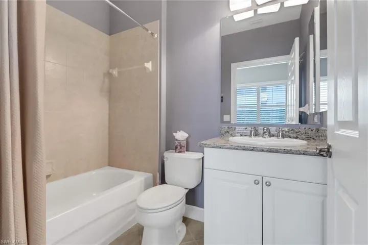 Full bathroom with shower / bath combination, vanity, toilet, and tile patterned flooring