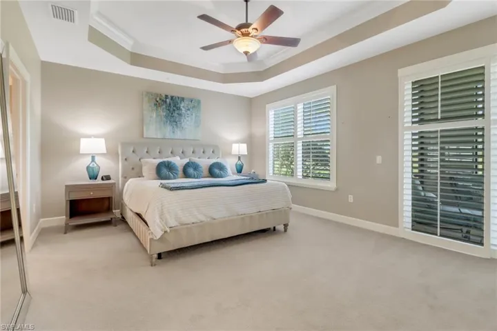 Bedroom featuring light colored carpet, ornamental molding, visible vents, a raised ceiling, and baseboards