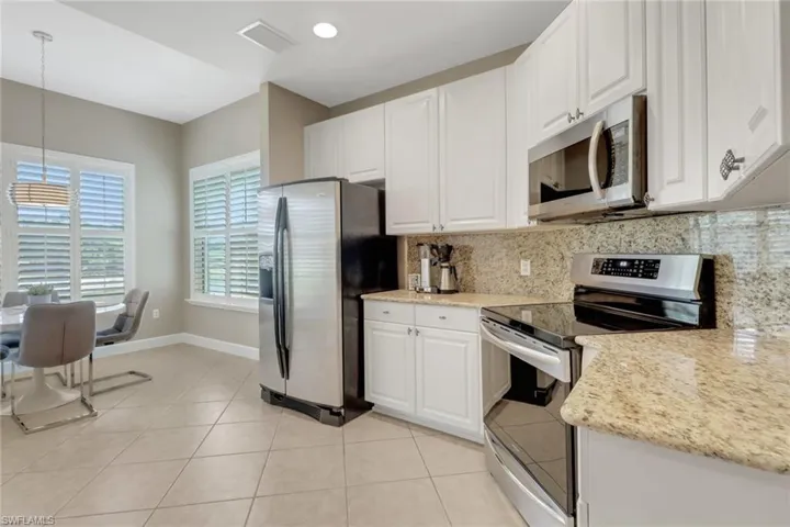 Kitchen featuring decorative light fixtures, tasteful backsplash, white cabinets, and appliances with stainless steel finishes