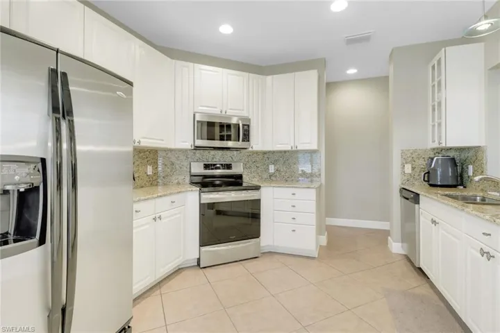 Kitchen featuring a sink, stainless steel appliances, tasteful backsplash, visible vents, and white cabinets