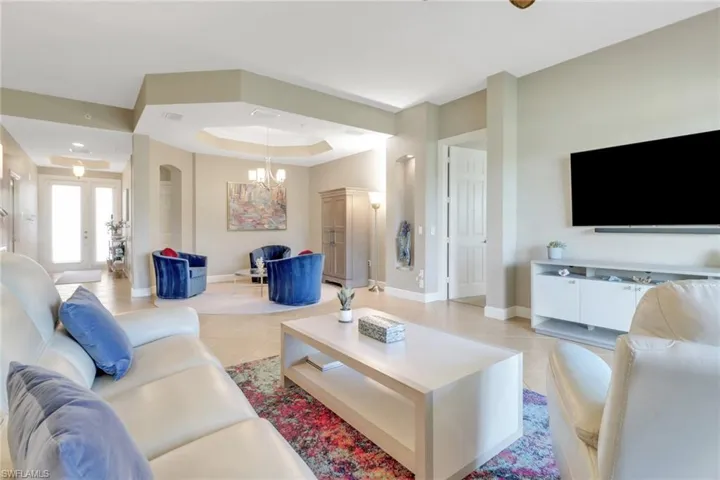 Living area featuring a raised ceiling, baseboards, and light tile patterned floors