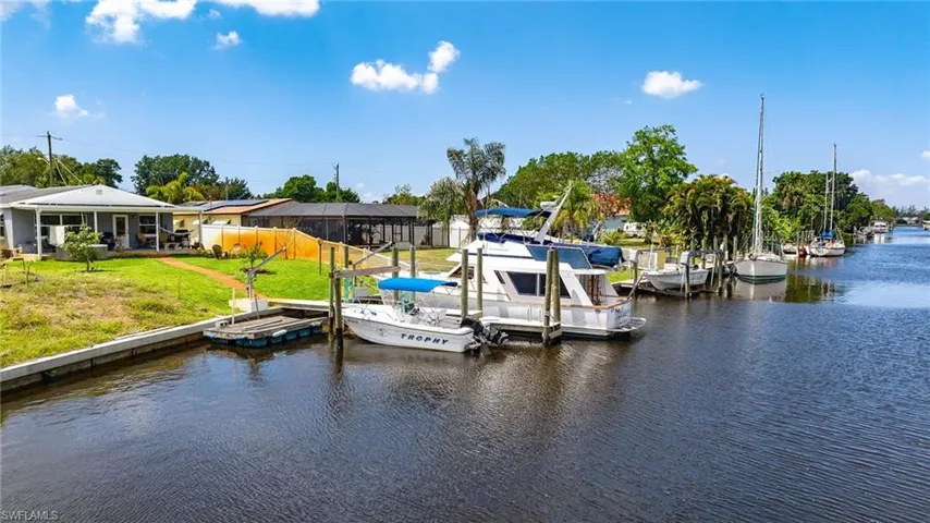 Dock area with a yard, fence, and a water view