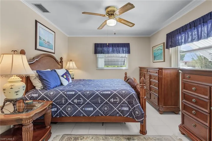 Bedroom with ornamental molding, visible vents, ceiling fan, and light tile patterned flooring